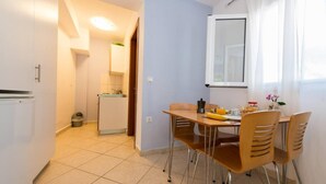 A compact kitchen with a refrigerator, sink, and a small dining area with a table and chairs. - Studio on Agia Efimia Seaside (Kefalonia)