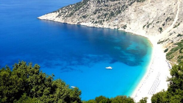 A coastal landscape with a beach, clear blue waters, and a boat. - Myrtos Cottages Cleo (Kefalonia)