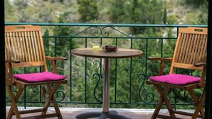 Ein Balkon mit zwei Holzstühlen und einem kleinen, runden Tisch.