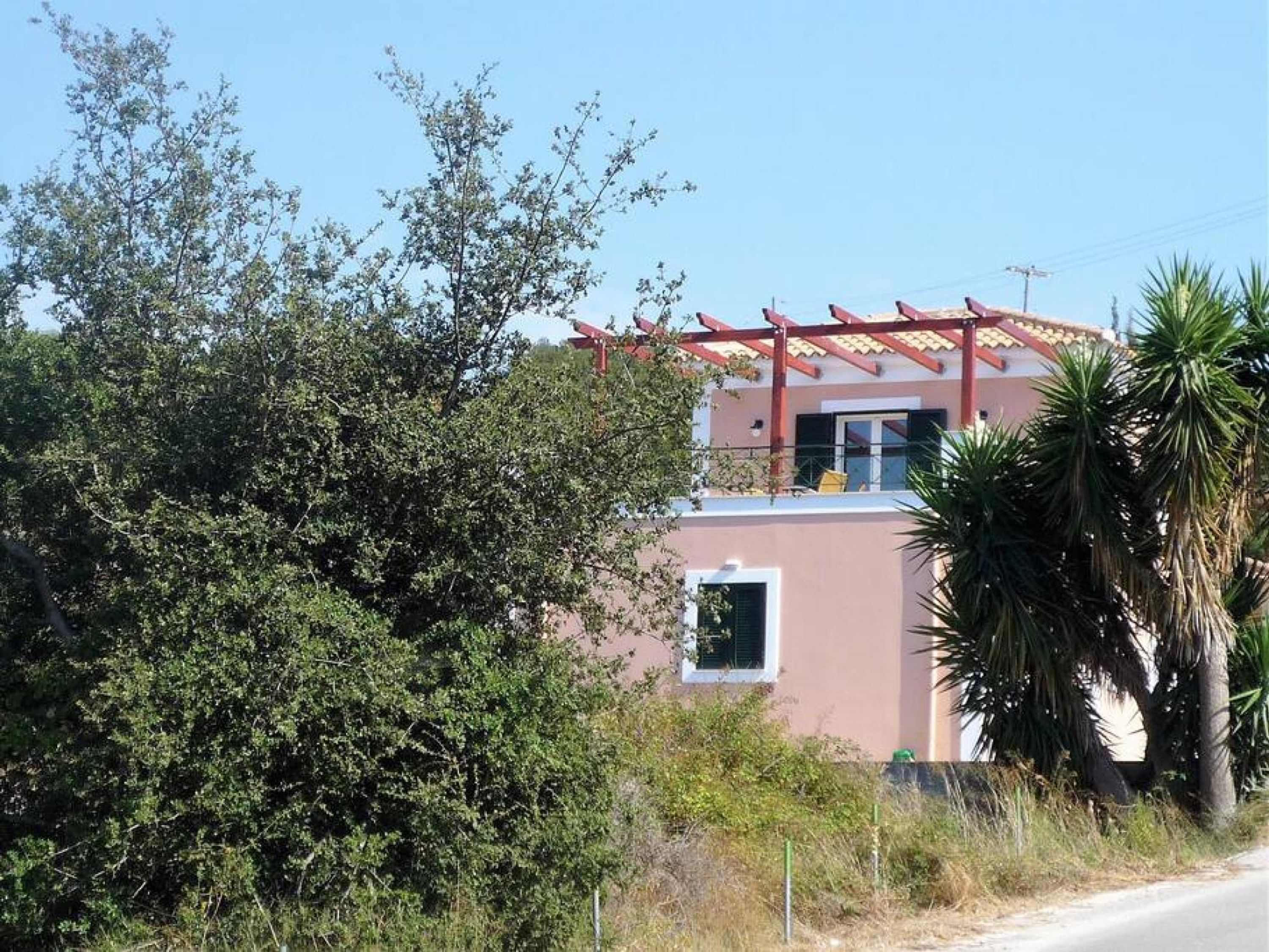 Een gebouw met twee verdiepingen, een balkon en een rode pergola.
