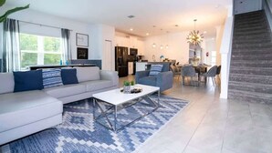 Ein modernes Wohnzimmer mit einer Couch, einem Couchtisch und einem Essbereich mit Stühlen und einem Tisch.