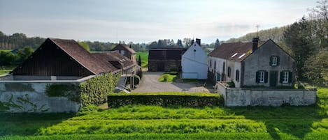 Une propriété rurale comprenant une grange, une maison blanche et un mur en pierre.