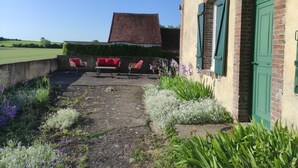Une terrasse avec des meubles d’extérieur, un bâtiment en briques et une vue sur la campagne.