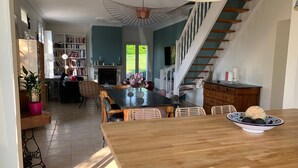 Un salón amplio con una mesa de comedor de madera, una escalera y una estantería llena de libros.