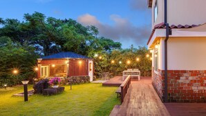 A well-lit outdoor area with a wooden deck, a small wooden structure, and string lights. - Jeju West Dokchae Pension (Jeju City)