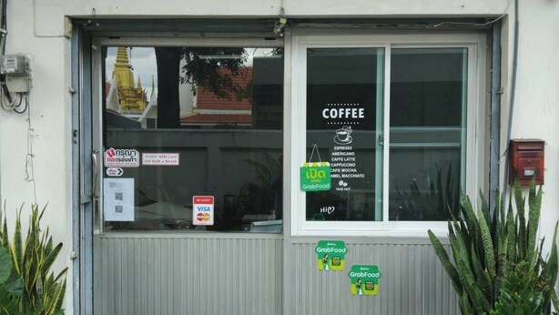 A hostel with a sign reading "Sleep with Me Hostel" and a cafe with a coffee menu.