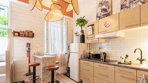 A modern kitchen with wooden cabinets, a black countertop, and a stainless steel sink. There are two stools and a small island with a bar stool. - Surfing-house Biarritz (Biarritz)
