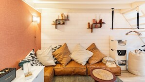A cozy living room with a brown leather sofa, patterned cushions, a small coffee table, and a wall-mounted shelf with decorative items. - Surfing-house Biarritz (Biarritz)