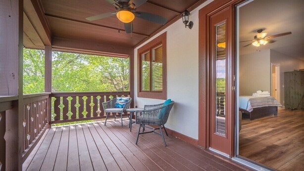 Um deck de madeira com um ventilador de teto, uma mesa e duas cadeiras.