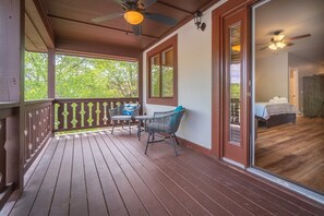 A wooden deck with a ceiling fan, a table, and two chairs.