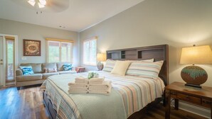 Quarto com cama, sofá, abajur e ventilador de teto.