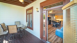 Une terrasse couverte avec une table et des chaises, un ventilateur de plafond et une vue sur un coin cuisine.