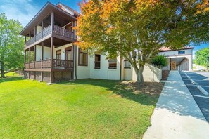 A two-story house with a balcony, a driveway, and a tree with autumn leaves.
