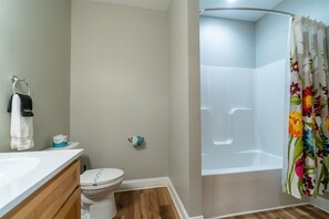 A bathroom with a toilet, sink, shower, and a floral shower curtain.