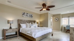 A bedroom with a wooden bed, two bedside tables, a ceiling fan, and a window with a view. - Dover Vistas - Ocean View w/ Rooftop Terrace, Firepit, Fast WiFi, AC & Parking! (San Diego)