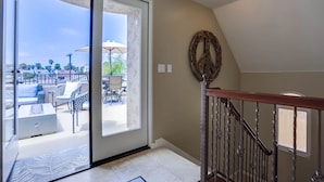 A spacious balcony with outdoor furniture and a sliding glass door leading to a patio area. - Dover Vistas - Ocean View w/ Rooftop Terrace, Firepit, Fast WiFi, AC & Parking! (San Diego)