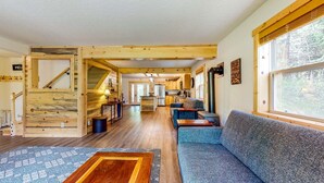 Een blokhutinterieur met een houten trap, een bank, een eethoek en een keuken.