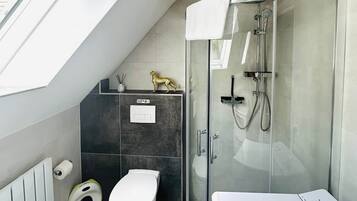 Et moderne badeværelse med en brusekabine med glasvægge, toilet og bidet.