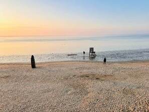 Una platja amb una cadira i una persona caminant.