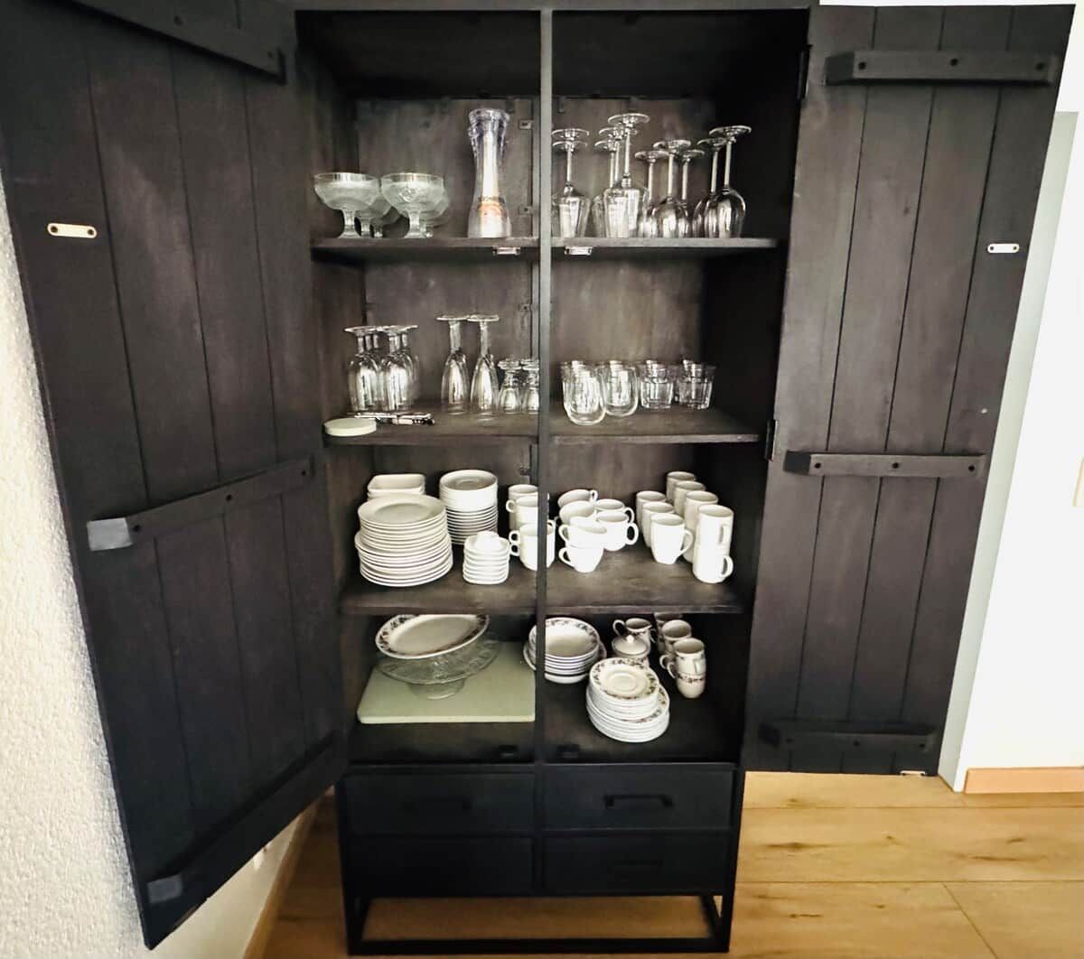 A black cabinet with multiple shelves containing various glassware and dishes.
