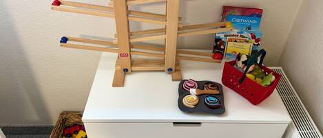 A white storage unit with a wooden toy ladder, colorful balls, and children's books.
