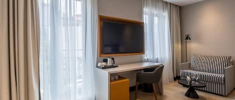 A modern hotel room with a desk, chair, and a sofa.