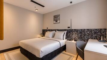 Una habitación de hotel moderna con una cama grande, un escritorio y una silla.