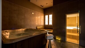 A modern bathroom with a large bathtub, a wooden bench, and a glass door leading to another room. - Cora Hotel (Split)