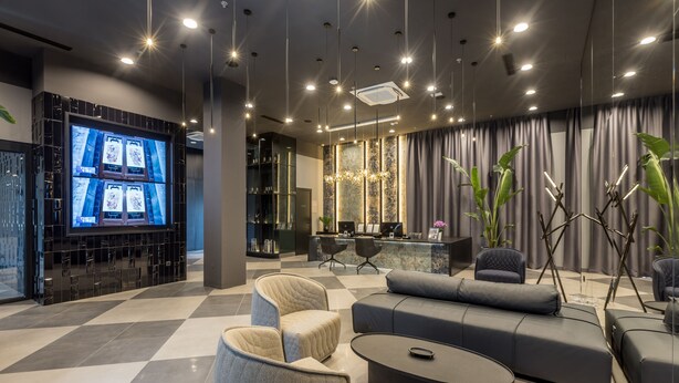 A modern hotel lobby with a checkered floor, a large flat-screen TV, comfortable seating, and a bar area. - Cora Hotel (Split)