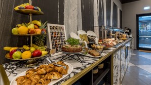 A buffet with various food items including fruits, pastries, and a cake.