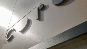 A metallic wall with a textured surface and a circular emblem.