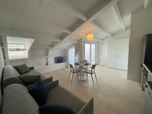A spacious loft apartment with a high ceiling, a dining area, and a TV in the living room. - IMHOME-ABRUZZI (Milan)