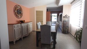 Un comedor con una mesa y sillas, un reloj decorativo en la pared y una vinoteca junto a la ventana.