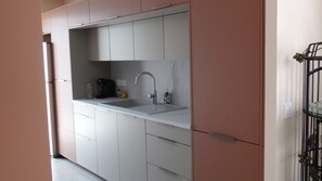A modern kitchen with white cabinets, a stainless steel sink, and a coffee maker.