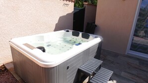 Un jacuzzi con panel de control, un escalón pequeño y una puerta.