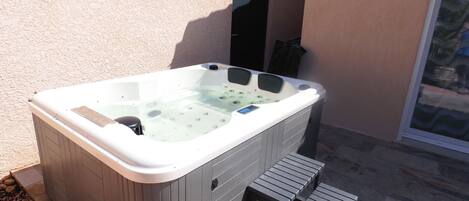 A hot tub with a control panel, a small step, and a door.