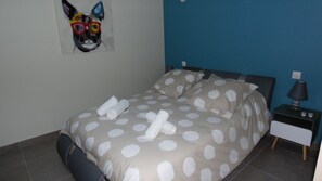 A bedroom with a bed, pillows, a nightstand, and a lamp.