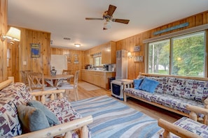 Un intérieur de chalet chaleureux comprenant un coin repas, un canapé et une cuisine.