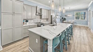 Una cocina moderna con armarios grises, encimera de mármol y una isla central con taburetes de bar.