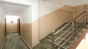 A corridor with a staircase leading to an upper floor. The walls are painted in two colors, and the floor has a patterned tile design.