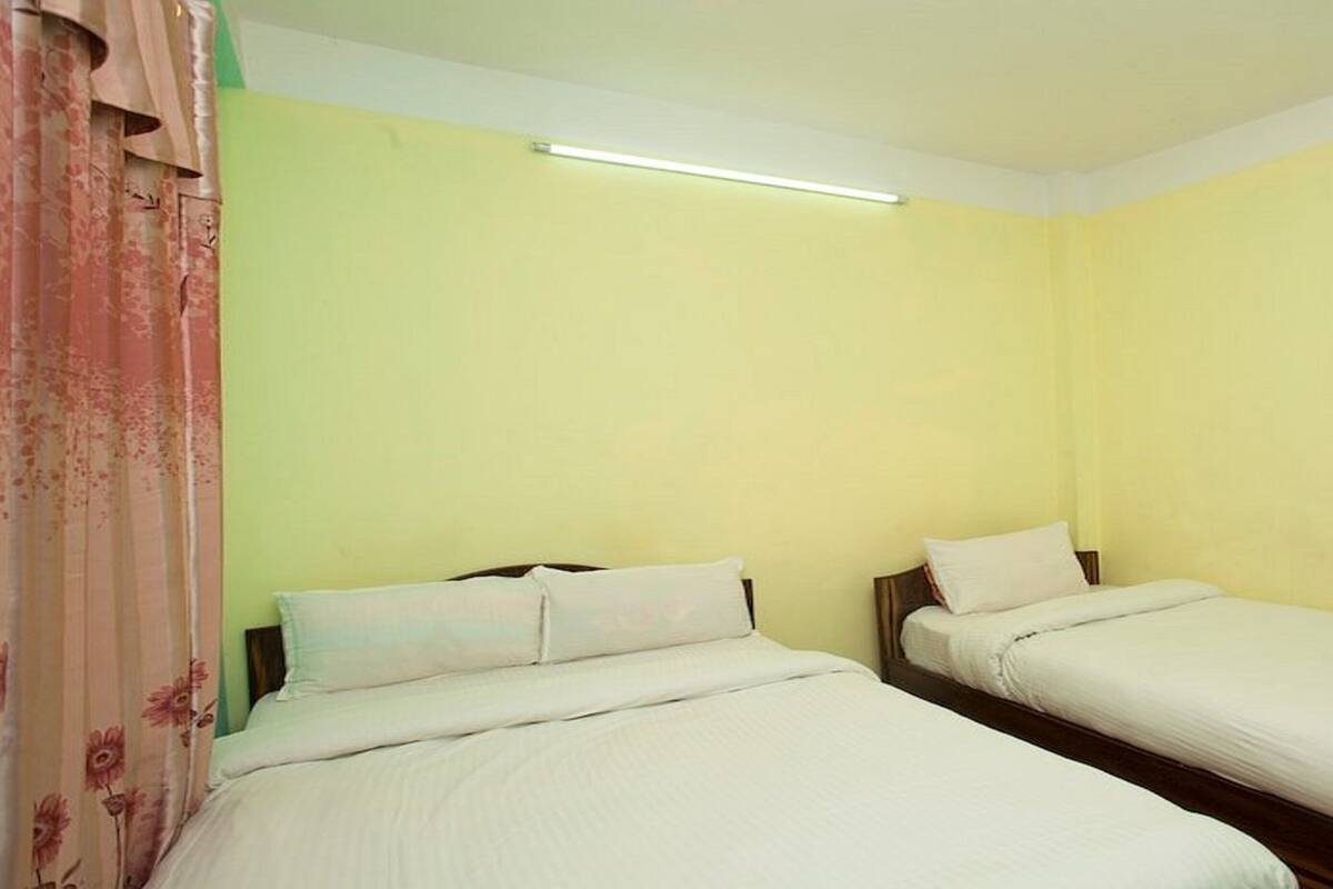 A room with two single beds, a light switch, and a power outlet on the wall.