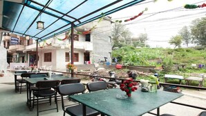 A restaurant with outdoor seating, a covered patio, and a view of the surrounding area.