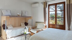 Un dormitorio acogedor con una litera, un sofá, una silla y un amplio ventanal con vistas al exterior.