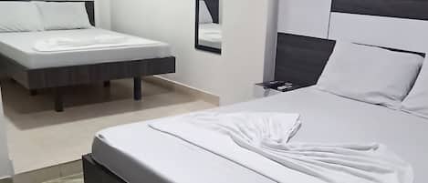 A hotel room with a large bed, a smaller bed, a nightstand, a mirror, and a wall-mounted air conditioner.