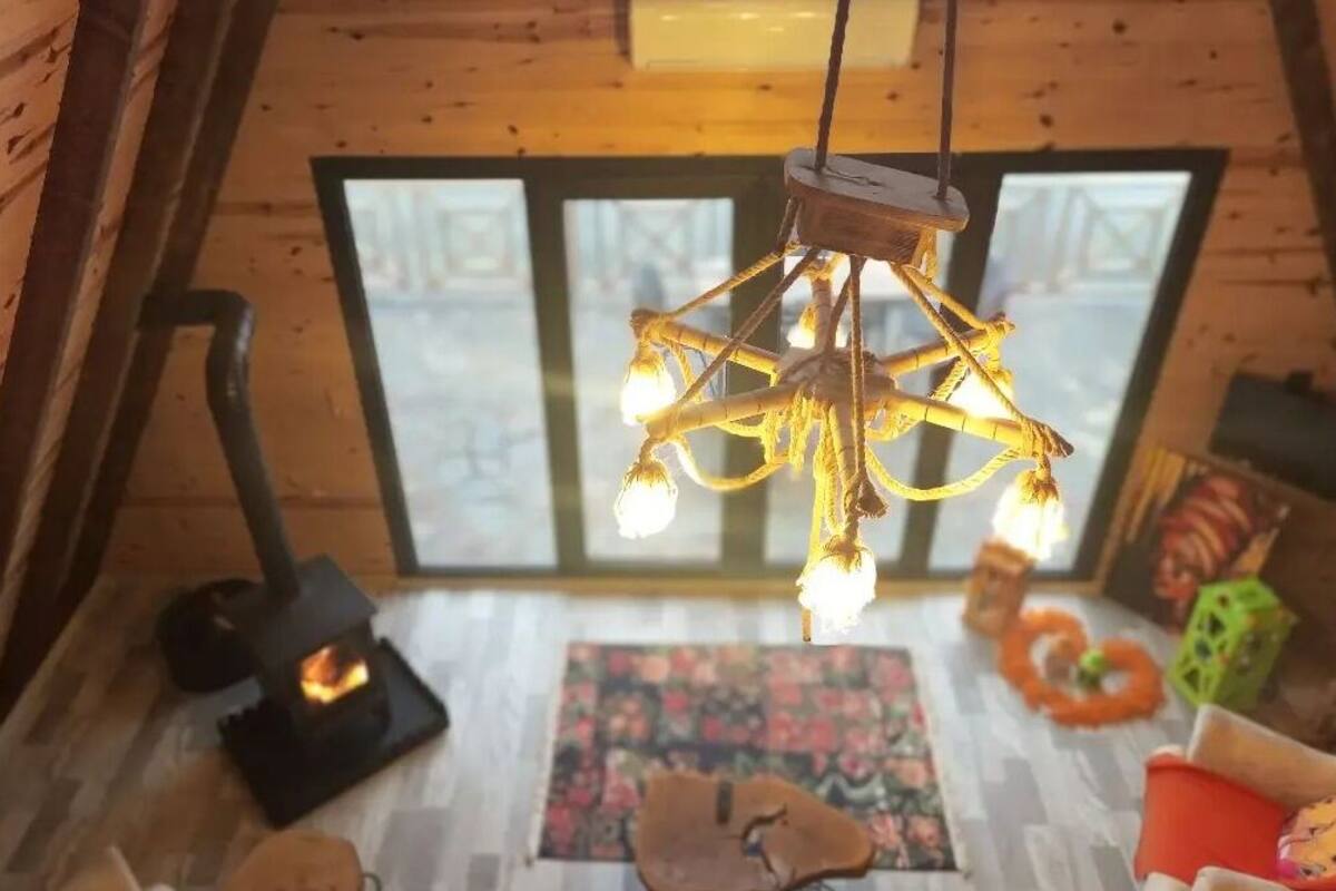 A cozy room with a star-shaped chandelier, a fireplace, and a large window.