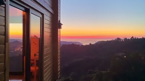 En træbygning med balkon med udsigt over en solnedgang.