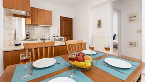 Un comedor con una mesa de madera, manteles individuales azules, platos blancos y un frutero.