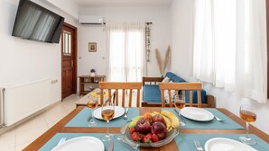 Un comedor con una mesa preparada para dos, un frutero y dos copas de vino.