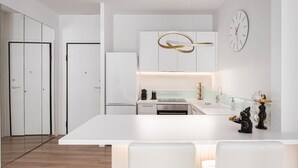 Una cocina moderna con armarios blancos, una isla central y un reloj fijado a la pared.