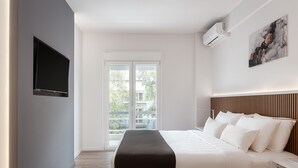 Un dormitorio moderno con una cama, un televisor de pantalla plana, una ventana y un equipo de aire acondicionado.